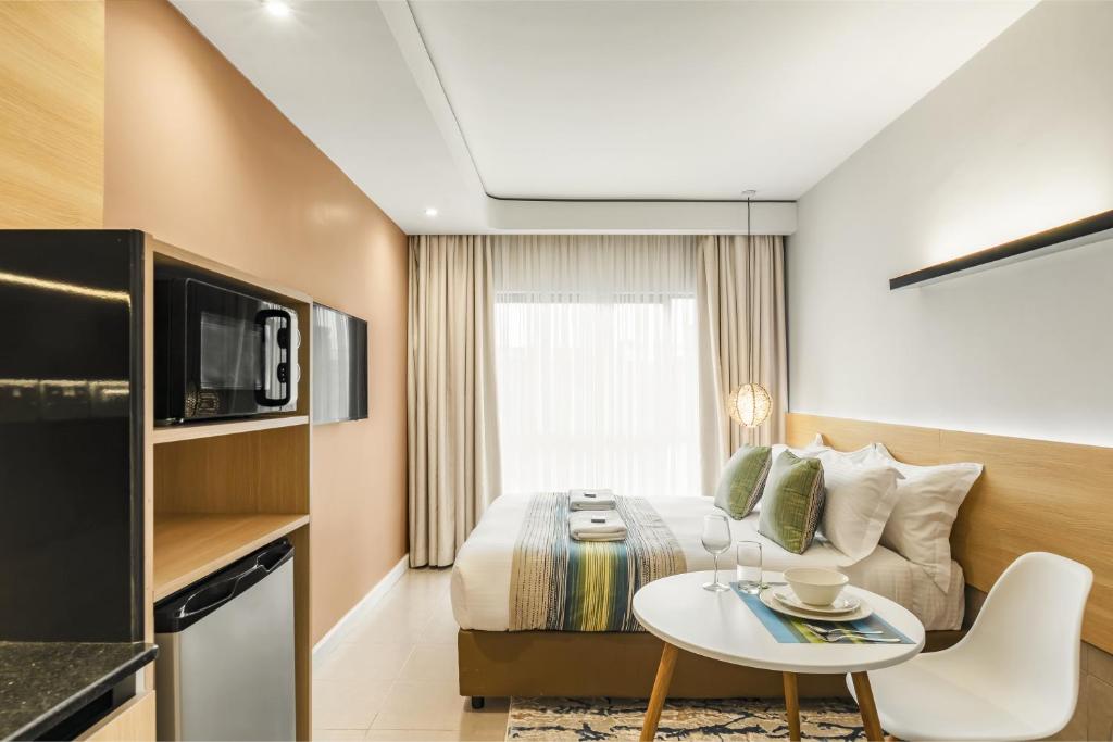 a hotel room with a bed and a table at Kozi Suites Nairobi Airport in Nairobi