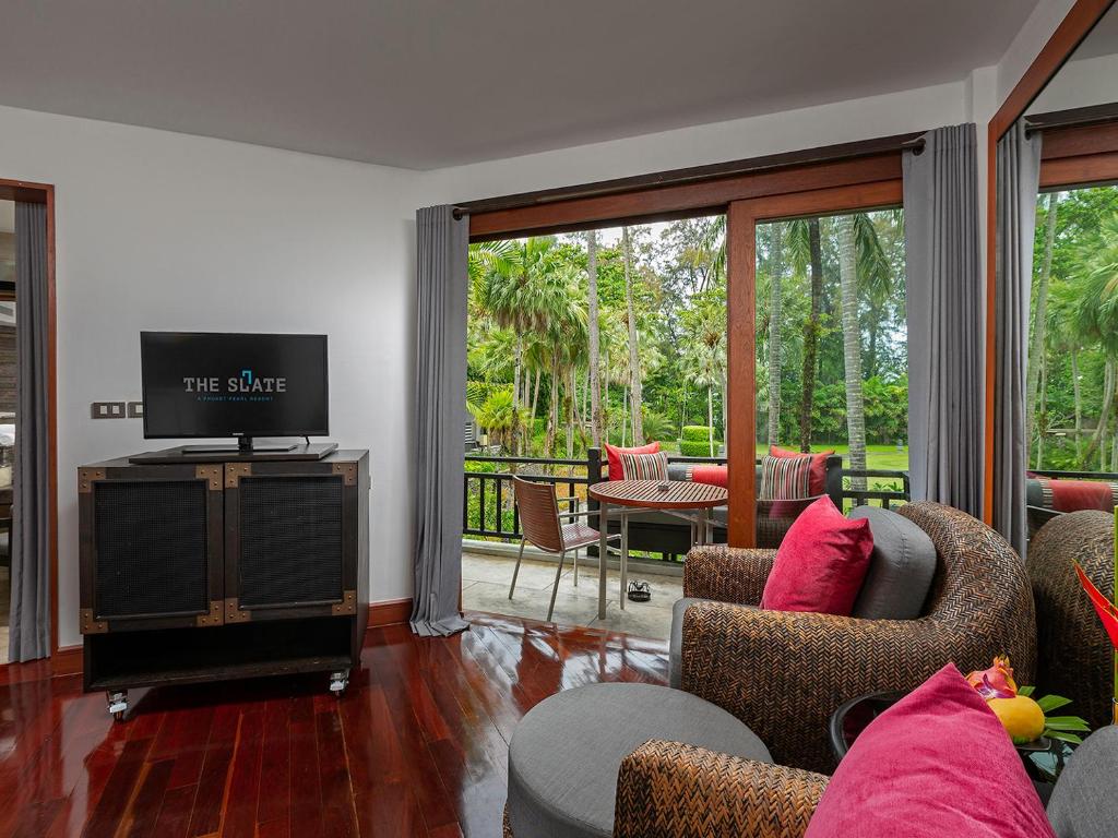 a living room with couches and a television and a patio at The Slate, Phuket in Nai Yang Beach
