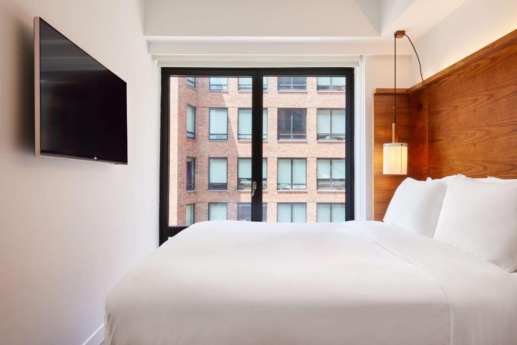 a bedroom with a large white bed and a window at Arlo SoHo in New York