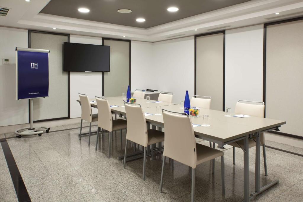 a conference room with a table and chairs and a screen at NH Madrid Atocha in Madrid