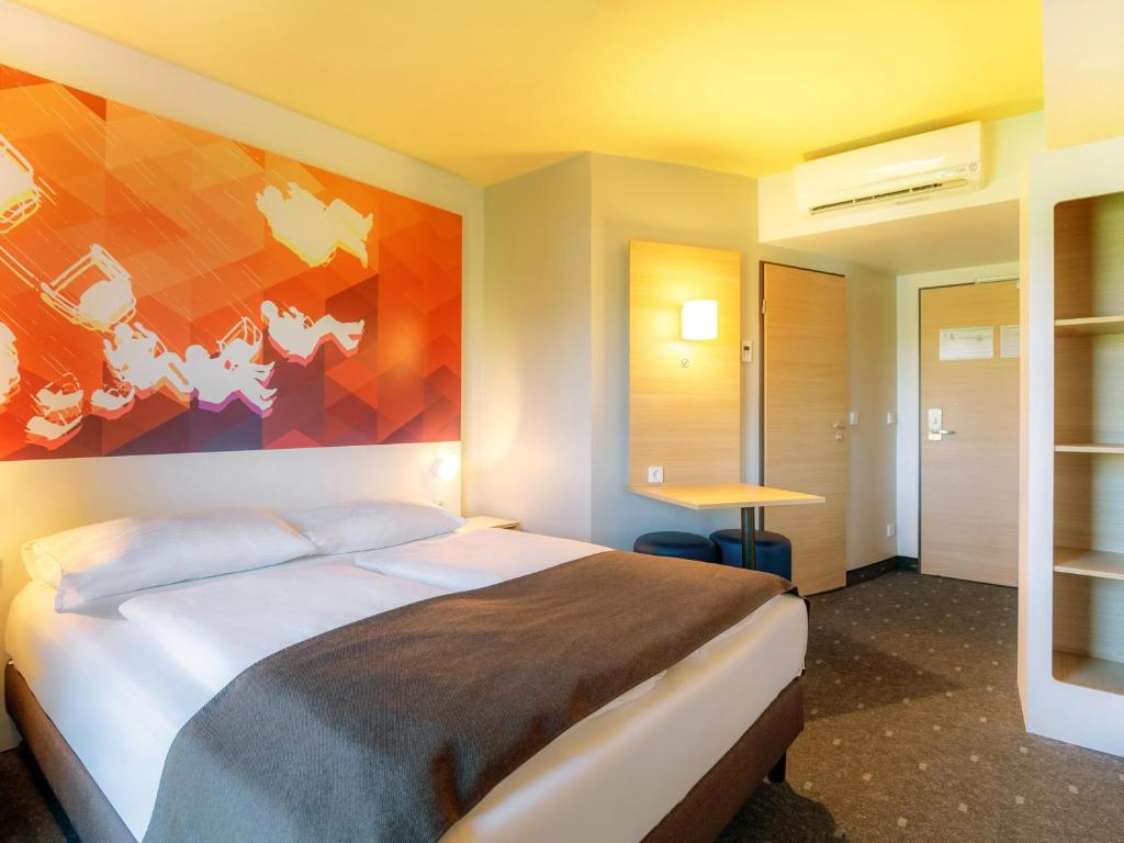 een slaapkamer met een bed met een schilderij aan de muur bij B&B Hotel Stuttgart-Bad Cannstatt in Stuttgart