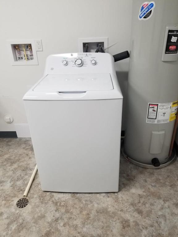a white washing machine sitting next to a trash can at Condo on State Hospital Grounds! in Traverse City