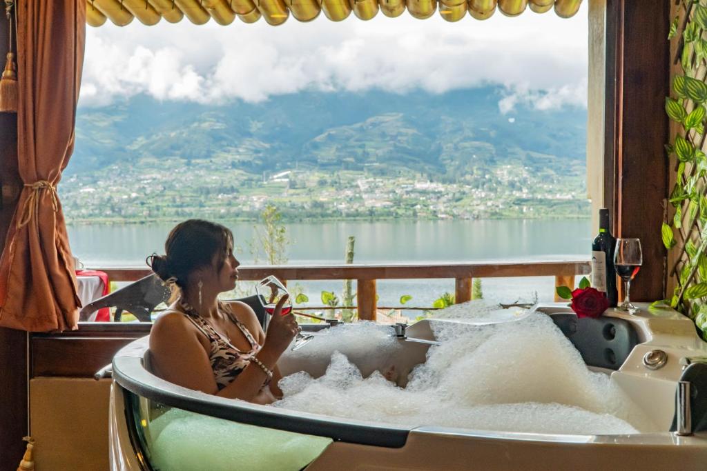 a woman sitting in a bath tub with a view at Hospedaje Campo Lago y Glamping in Otavalo