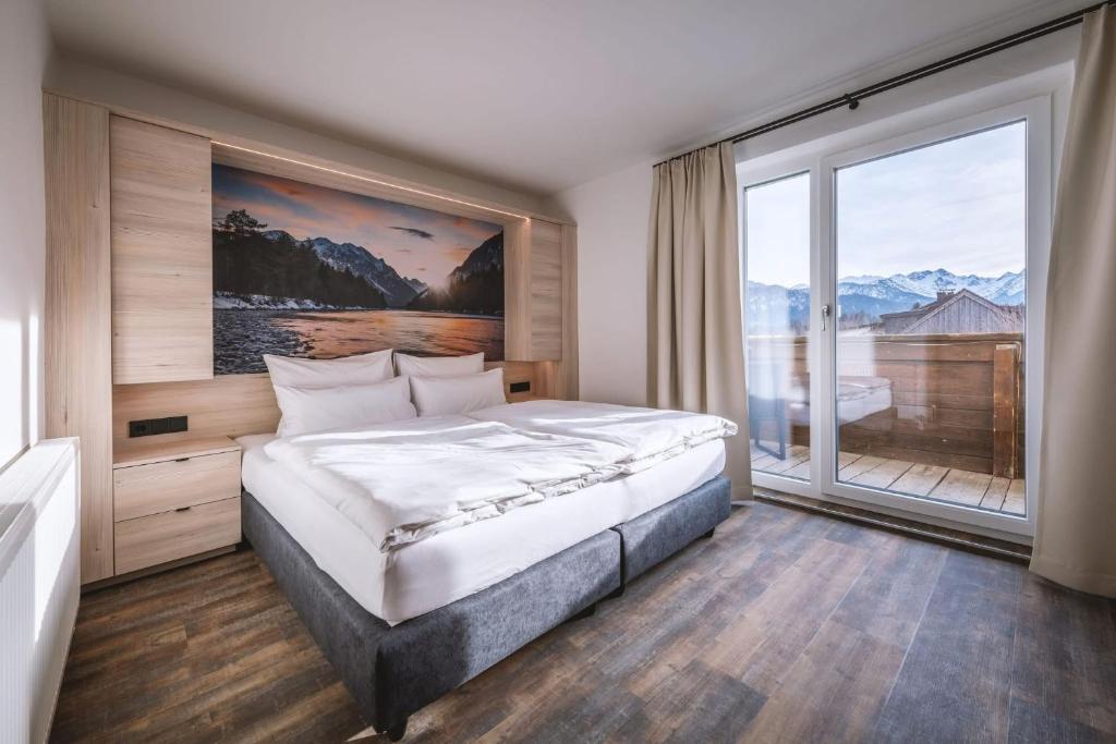 een slaapkamer met een groot bed en een groot raam bij Hotel Lainbach in Wängle in Reutte