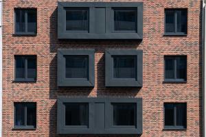 a brick building with black windows on it at Munich Deluxe Hotel in Munich