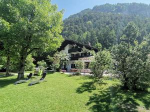 a house in the middle of a yard with trees at Pension Almhof Baumgarten in Bad Reichenhall