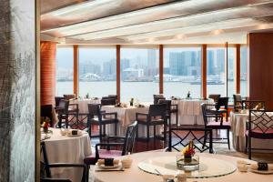 a restaurant with tables and chairs and a view of the water at Four Seasons Hotel Hong Kong in Hong Kong