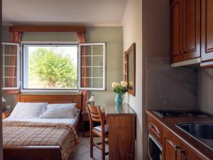 a small bedroom with a bed and a table and a window at Villa Maria Laganas in Laganas