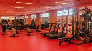 a gym with rows of exercise equipment on a red floor at The Standard Miami in Miami Beach