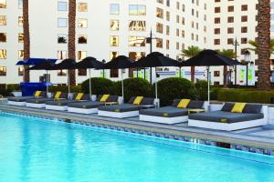 a row of lounge chairs and umbrellas next to a swimming pool at Planet Hollywood Resort & Casino in Las Vegas