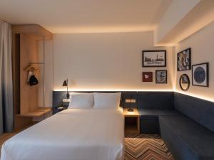 um quarto com uma grande cama branca e um sofá em Hampton By Hilton Munich City North em Munique mais 32 fotografias