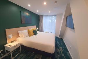 a bedroom with a large bed and a green wall at La Quinta by Wyndham Ellerslie Auckland in Auckland +37 photos
