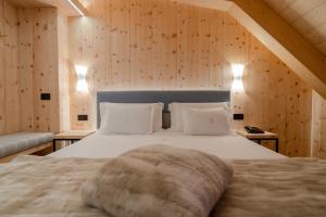 una camera da letto con un grande letto bianco e pareti in legno di Hotel San Lorenzo a Bormio Altre 37 foto