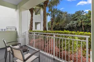 a balcony with two chairs and palm trees at Provident Doral At The Blue in Miami