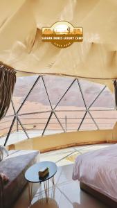 a bedroom with a large window with a bed and a table at RUM SAHARA DUNES lUXURY CAMP in Wadi Rum