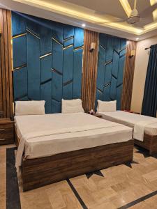 two beds in a room with blue walls at Gulshan Palace Hotel in Karachi