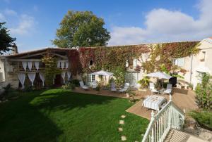 a house with a yard with chairs and tables at La Tillaie SPA et Sauna in Pont-lʼAbbé-dʼArnoult