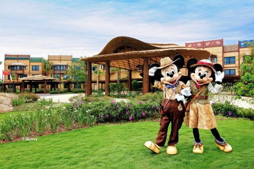 two people dressed in mickey mouse costumes standing in the grass at Disney Explorers Lodge in Hong Kong