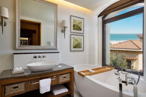 a bathroom with a tub and a sink and a window at The St. Regis Saadiyat Island Resort, Abu Dhabi in Abu Dhabi