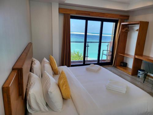 a bedroom with a large bed with a view of the ocean at AIMI Beach Hotel in Gulhi